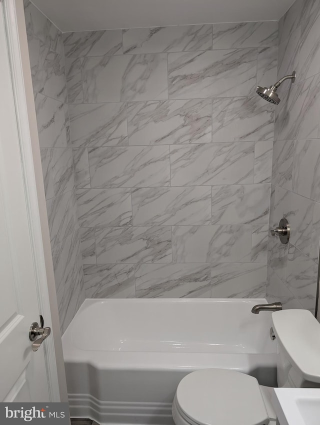 bathroom with tiled shower / bath combo and toilet