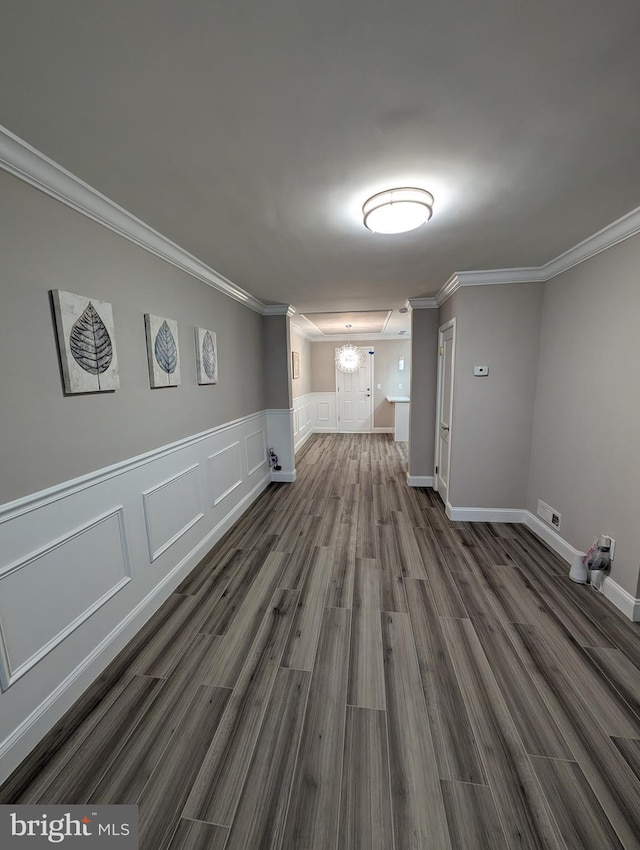 spare room featuring dark wood-type flooring, ornamental molding, and a chandelier