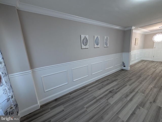 spare room with a notable chandelier, crown molding, and hardwood / wood-style flooring