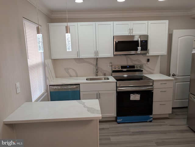 kitchen with stainless steel appliances, crown molding, white cabinets, and decorative light fixtures