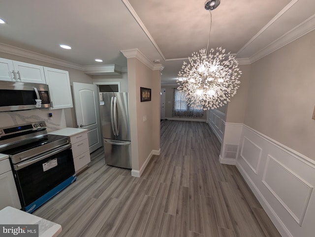 kitchen with white cabinetry, hardwood / wood-style flooring, ornamental molding, and stainless steel appliances