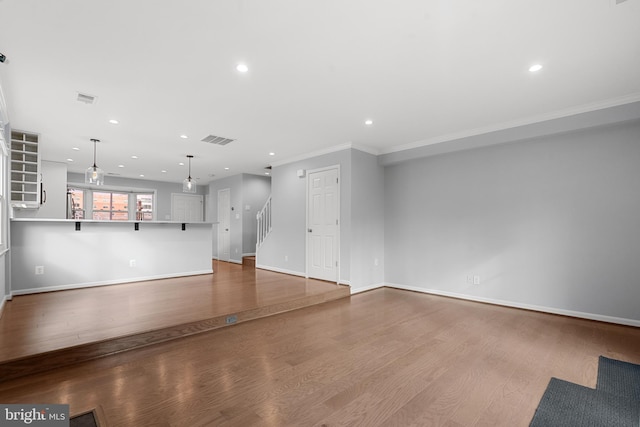 unfurnished living room with crown molding and wood-type flooring