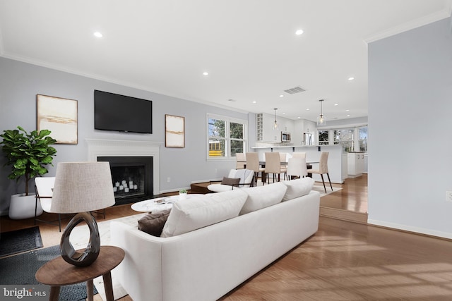 living room with ornamental molding and light hardwood / wood-style flooring