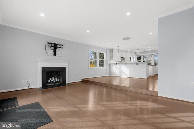 unfurnished living room featuring crown molding and hardwood / wood-style flooring