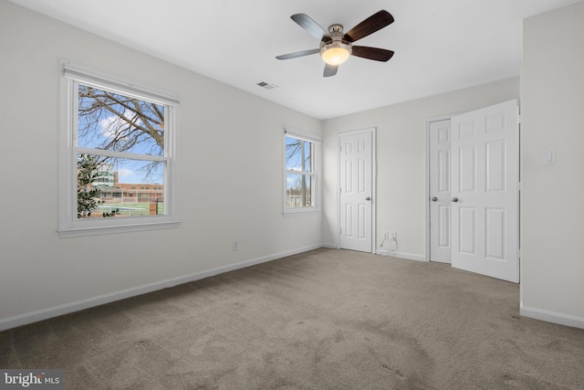 unfurnished bedroom with ceiling fan, carpet, and two closets