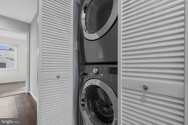 washroom with stacked washer / drying machine and dark hardwood / wood-style flooring