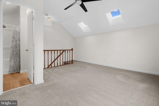 bonus room with light colored carpet, lofted ceiling with skylight, and ceiling fan