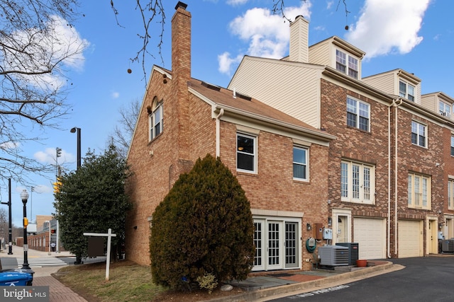 back of property with central AC unit and a garage