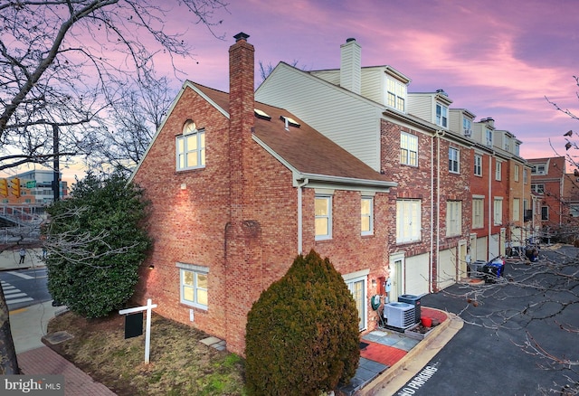 property exterior at dusk with a garage and central air condition unit