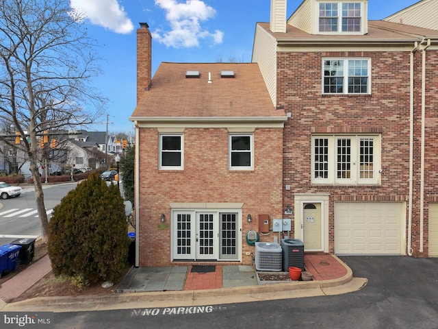 rear view of house featuring a garage and central AC