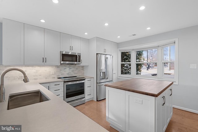 kitchen featuring butcher block counters, appliances with stainless steel finishes, sink, and white cabinets