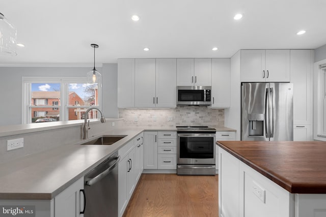 kitchen featuring pendant lighting, white cabinetry, sink, decorative backsplash, and stainless steel appliances