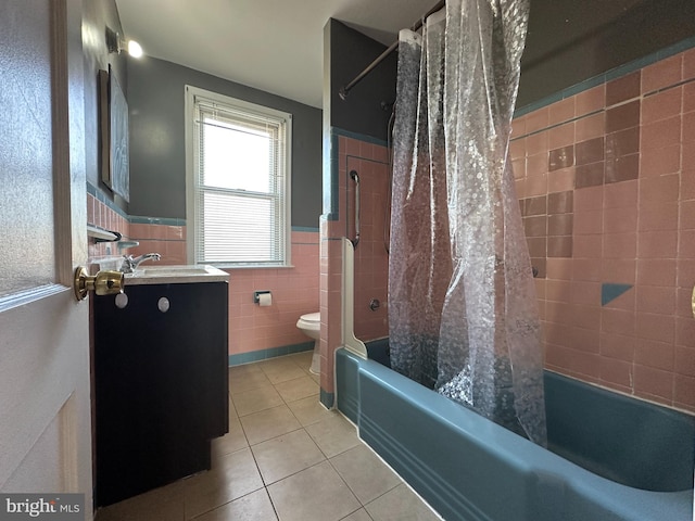 full bathroom with tile walls, shower / bath combination with curtain, tile patterned flooring, vanity, and toilet