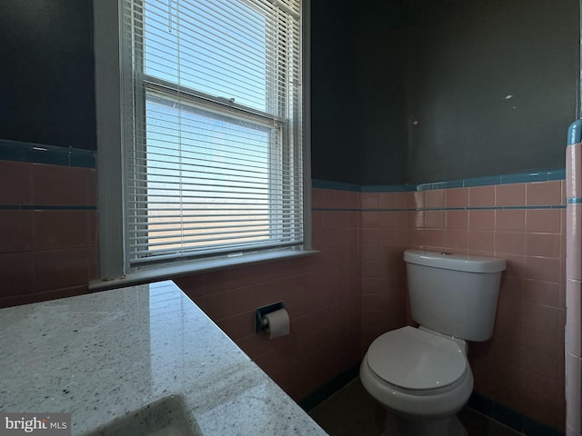 bathroom featuring tile walls and toilet