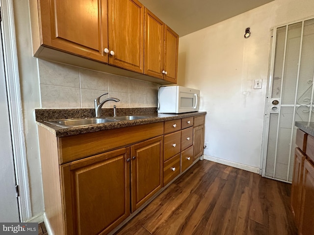 kitchen featuring dark hardwood / wood-style flooring, sink, and decorative backsplash