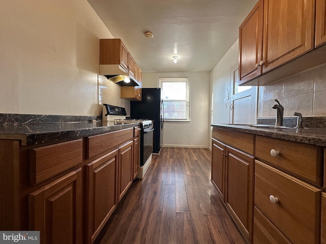 kitchen with sink, decorative backsplash, gas stove, and dark stone counters