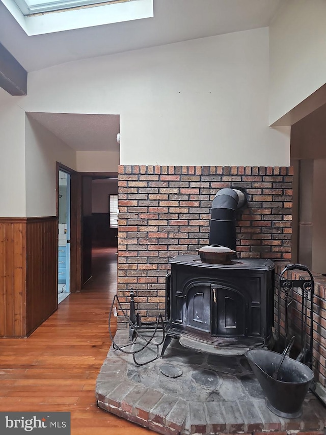 interior details featuring wood walls, a skylight, hardwood / wood-style floors, and a wood stove