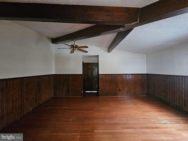 spare room featuring ceiling fan, lofted ceiling with beams, a textured ceiling, and light wood-type flooring