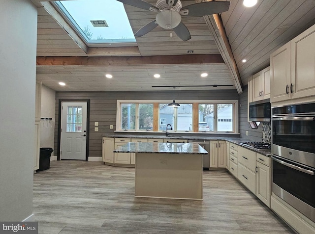 kitchen featuring wooden ceiling, dark stone countertops, a kitchen island, stainless steel appliances, and beam ceiling