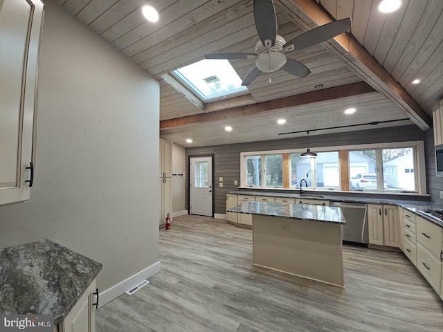 kitchen with a healthy amount of sunlight, dark stone counters, dishwasher, and a kitchen island