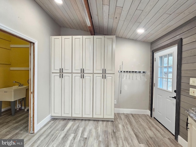 interior space featuring wooden walls, vaulted ceiling with beams, wood ceiling, and light wood-type flooring