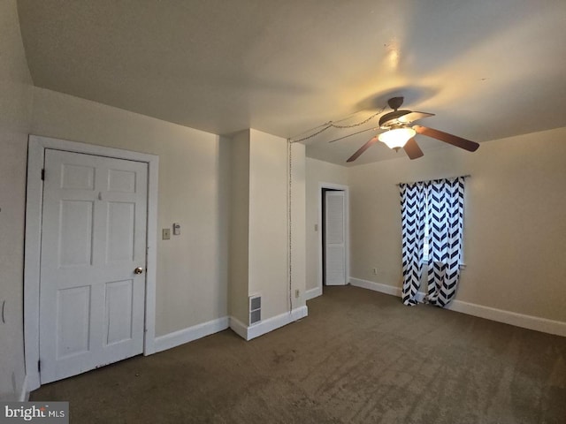 unfurnished room featuring ceiling fan and dark colored carpet