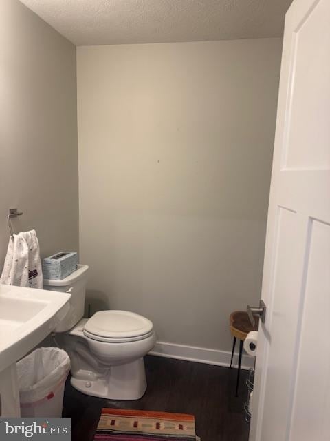 bathroom featuring wood-type flooring, a textured ceiling, and toilet