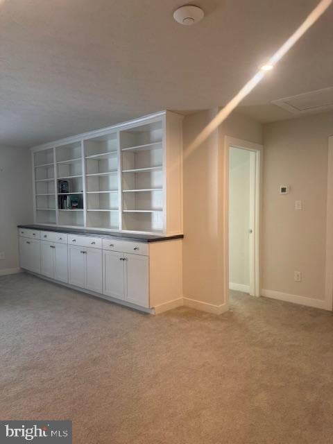 kitchen featuring white cabinetry, light carpet, and built in features