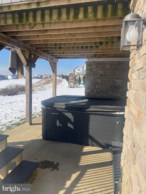 snow covered patio featuring a hot tub