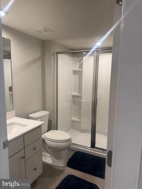 bathroom featuring vanity, toilet, and a shower with door