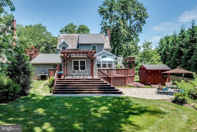 rear view of property with a patio, a deck, a storage unit, a yard, and a pergola