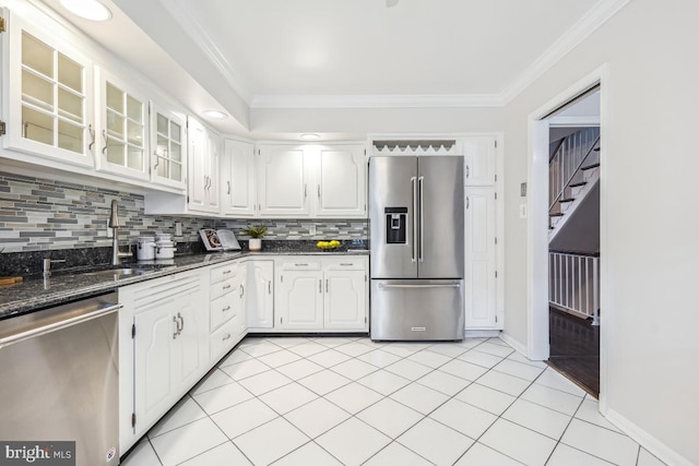 kitchen with dark stone countertops, ornamental molding, white cabinets, and appliances with stainless steel finishes