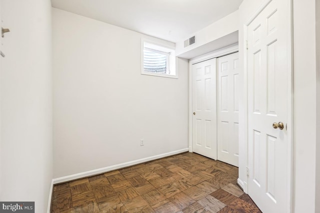 unfurnished bedroom with dark parquet floors and a closet