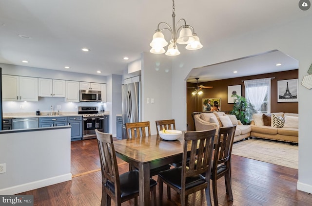 dining space with dark hardwood / wood-style flooring, sink, and ceiling fan with notable chandelier