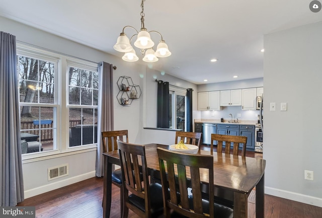 dining space with dark wood-type flooring, an inviting chandelier, and sink