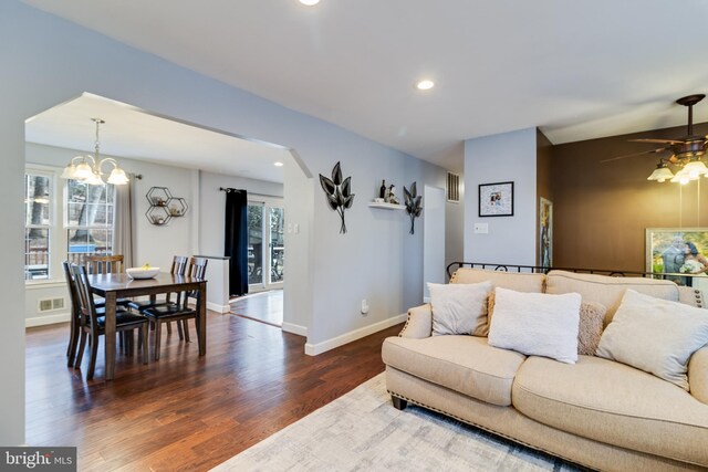 living room with dark hardwood / wood-style flooring and ceiling fan with notable chandelier