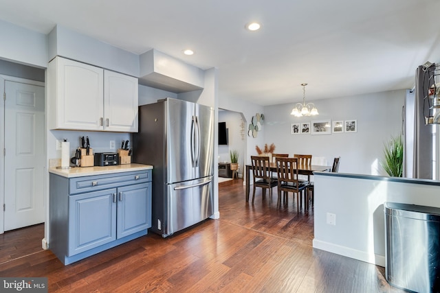 kitchen with decorative light fixtures, a chandelier, stainless steel refrigerator, dark hardwood / wood-style flooring, and white cabinets