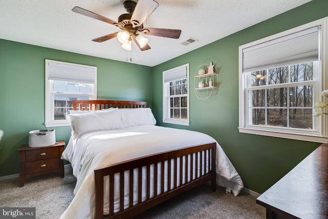 bedroom with ceiling fan, carpet flooring, and a textured ceiling