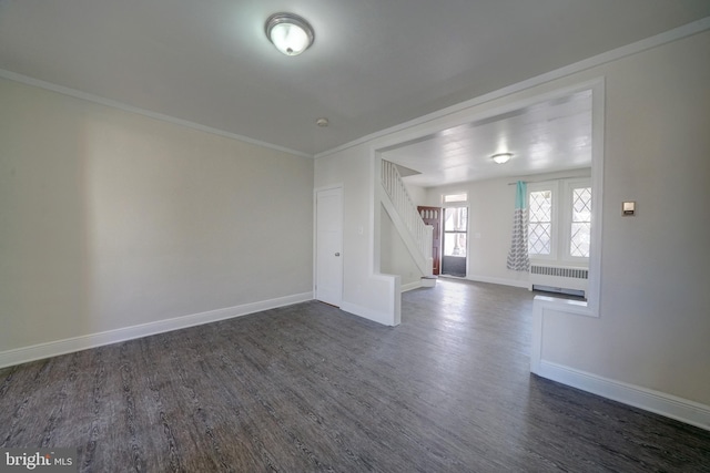 empty room with dark hardwood / wood-style flooring, crown molding, and radiator heating unit