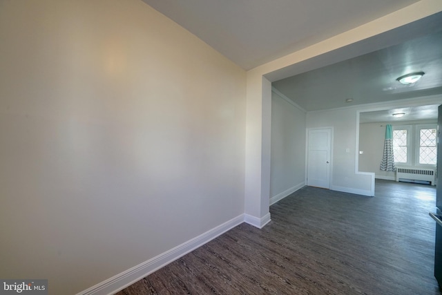 empty room with dark hardwood / wood-style flooring and radiator