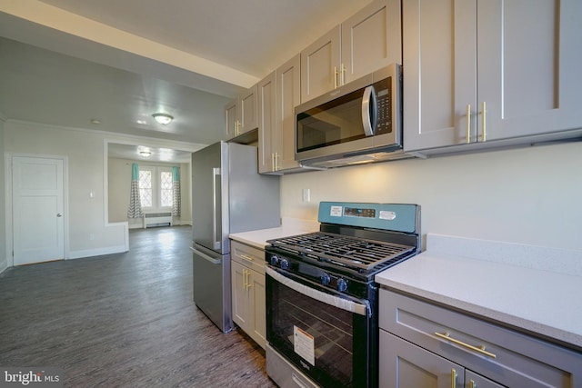 kitchen with appliances with stainless steel finishes, dark hardwood / wood-style flooring, gray cabinets, and radiator