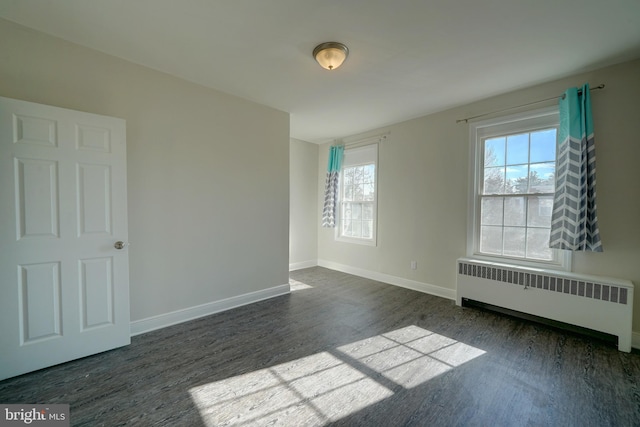 spare room featuring radiator heating unit and dark hardwood / wood-style floors