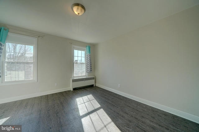 spare room with dark wood-type flooring and radiator heating unit