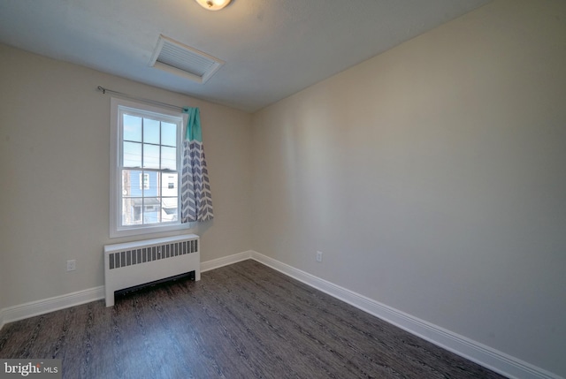 empty room with radiator and dark hardwood / wood-style floors