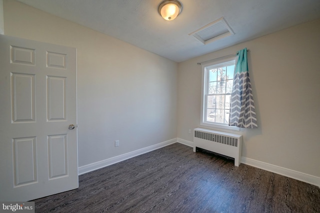 empty room with radiator and dark hardwood / wood-style floors