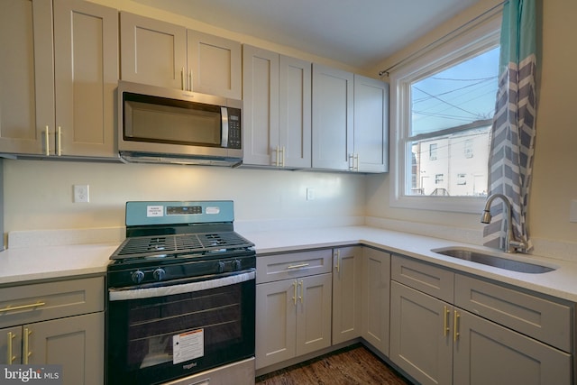 kitchen featuring appliances with stainless steel finishes, sink, gray cabinetry, and dark hardwood / wood-style flooring