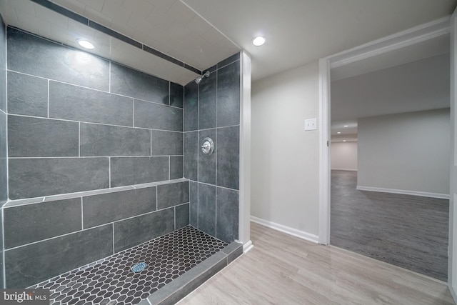 bathroom with wood-type flooring and a tile shower