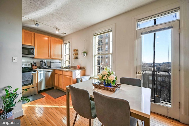 kitchen featuring appliances with stainless steel finishes, sink, light hardwood / wood-style floors, and a textured ceiling