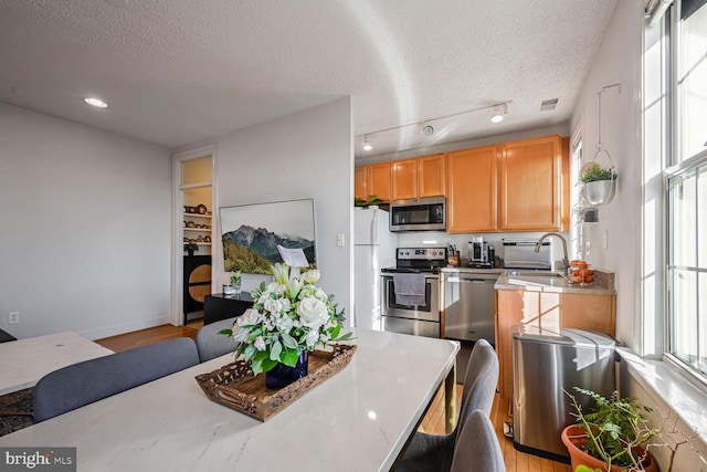 kitchen featuring appliances with stainless steel finishes, sink, light hardwood / wood-style flooring, and a textured ceiling