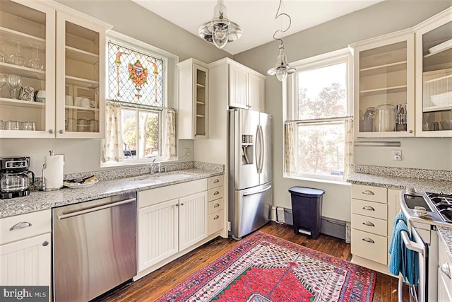 kitchen with stainless steel appliances, white cabinetry, sink, and decorative light fixtures